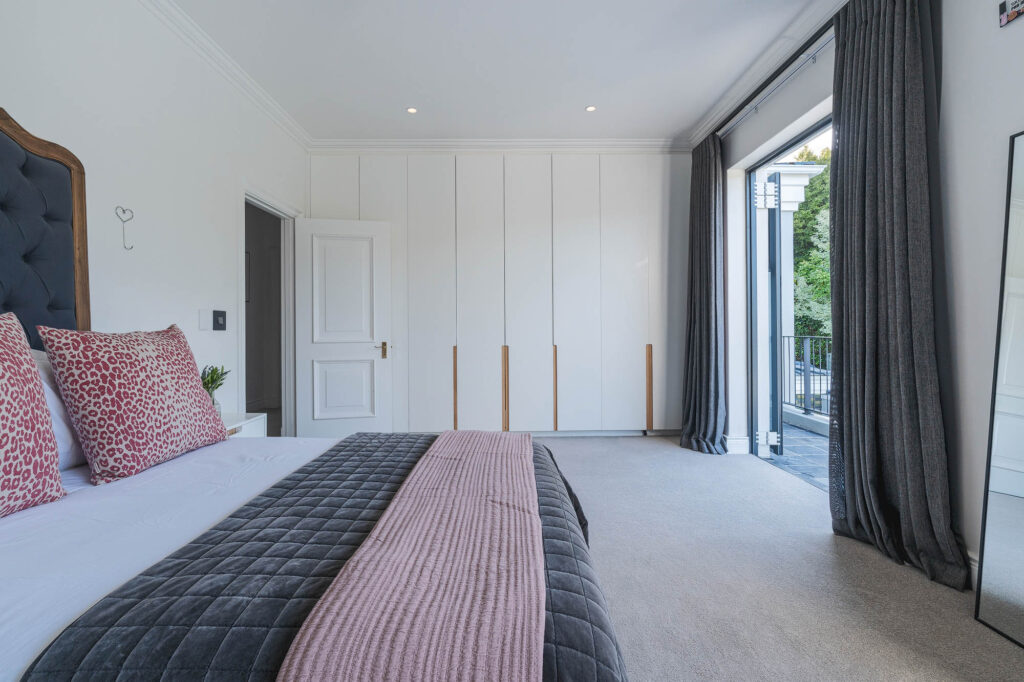 A spacious and elegantly designed bedroom, soft neutral tones, large windows offering natural light