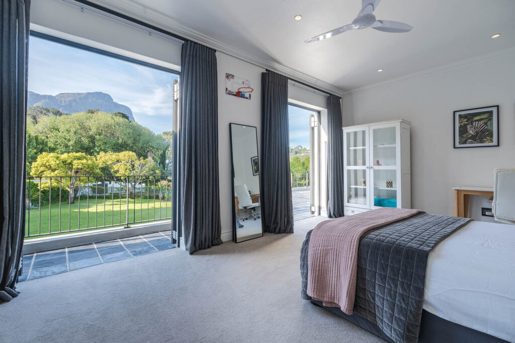 A spacious and elegantly designed bedroom, soft neutral tones, large windows offering natural light