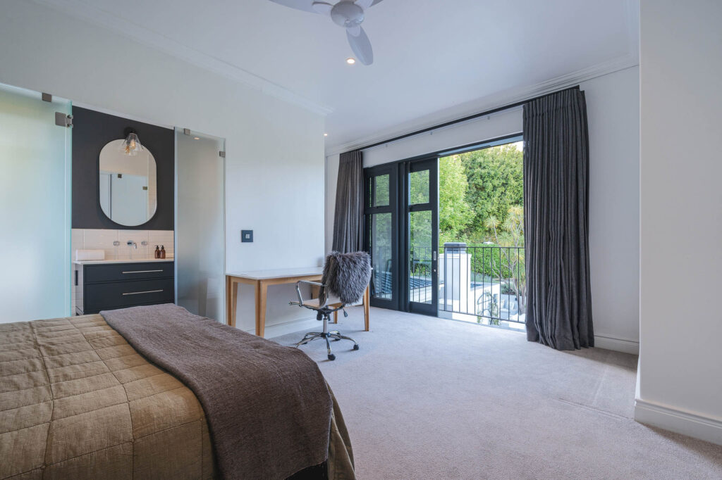 A spacious and elegantly designed bedroom, soft neutral tones, large windows offering natural light