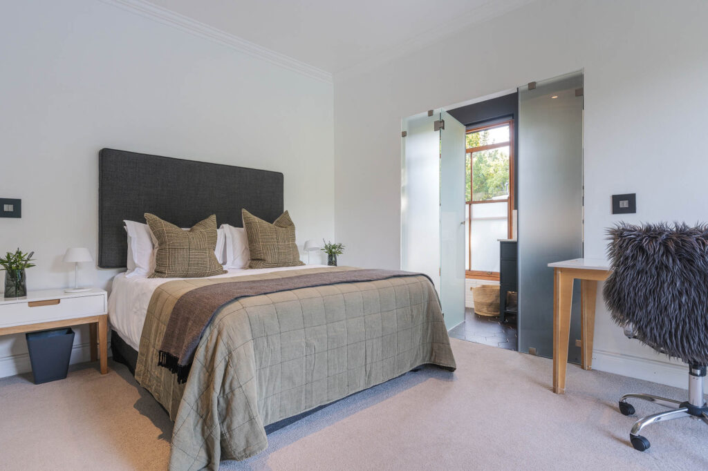 A spacious and elegantly designed bedroom, soft neutral tones, large windows offering natural light